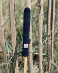 Mairead Hume® Black Watch Tartan Harris Tweed® Golf Alignment Stick Cover — outdoor lifestyle shot leaning against a natural fence