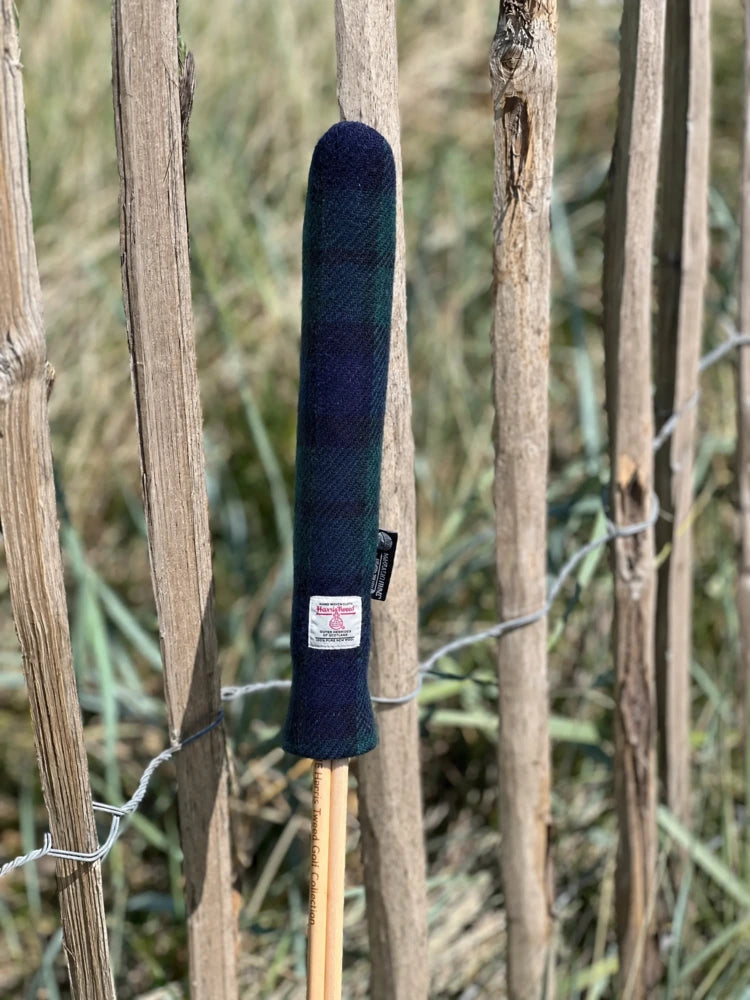 Mairead Hume® Black Watch Tartan Harris Tweed® Golf Alignment Stick Cover — outdoor lifestyle shot leaning against a natural fence
