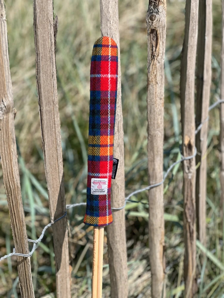Mairead Hume® Buchanan Tartan Harris Tweed® Golf Alignment Stick Cover — outdoor lifestyle shot leaning against a natural fence