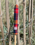Mairead Hume® Buchanan Tartan Harris Tweed® Golf Alignment Stick Cover — outdoor lifestyle shot leaning against a natural fence