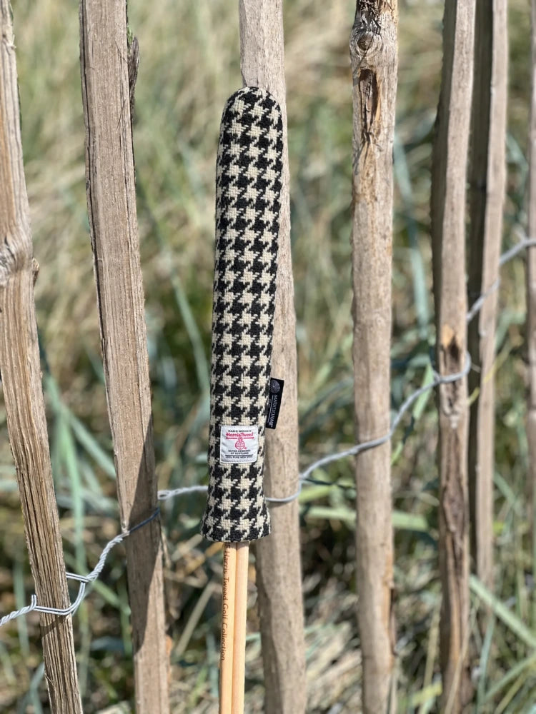 Mairead Hume® Black &amp; White Houndstooth Harris Tweed® Golf Alignment Stick Cover — outdoor lifestyle shot leaning against a natural fence