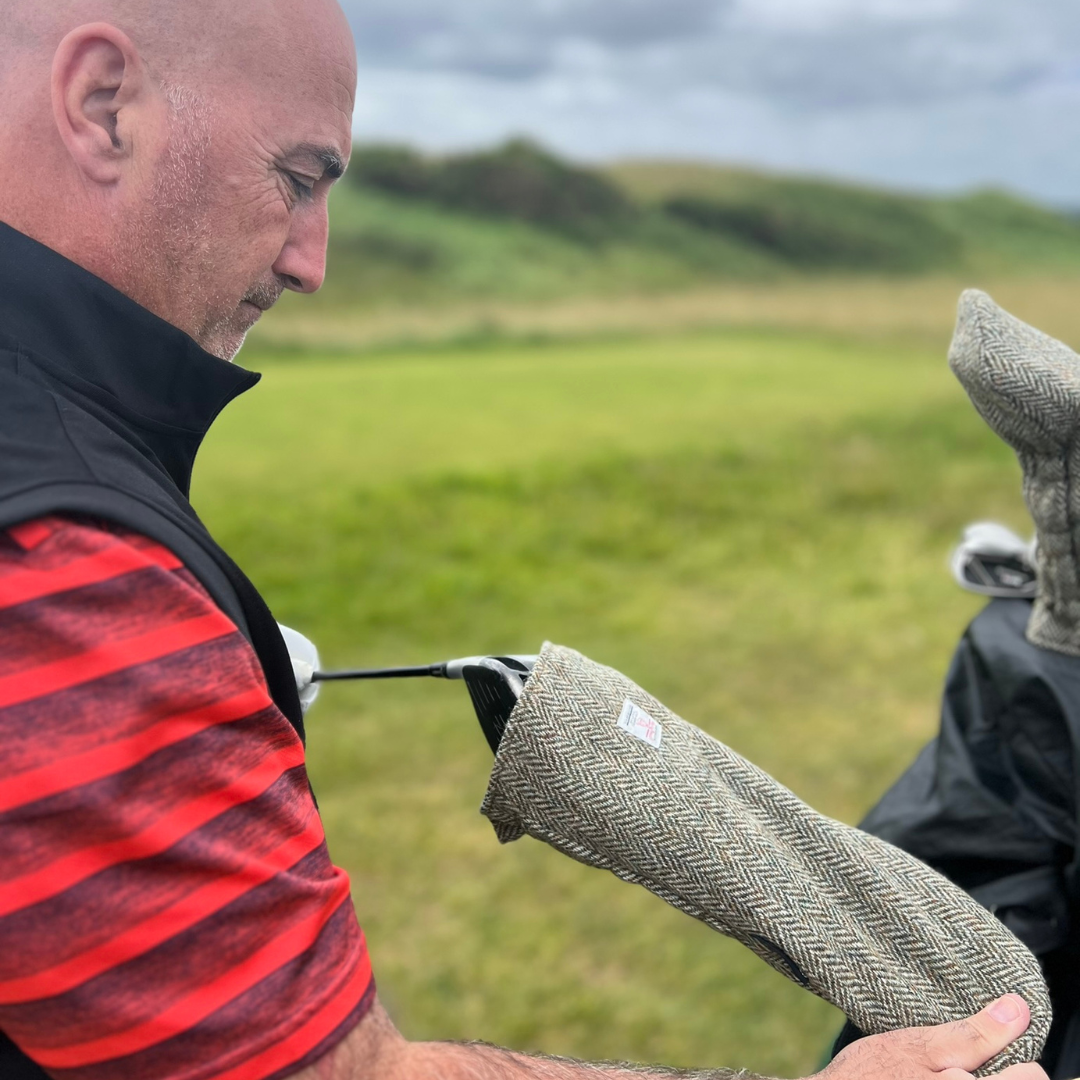 Man holding a golf club with a textured grip on a grassy field
