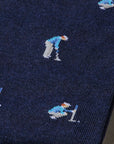 A close-up of a navy blue knit fabric, likely a scarf or sweater, featuring a repeating pattern of small pixelated hockey players in light blue, white, and orange.